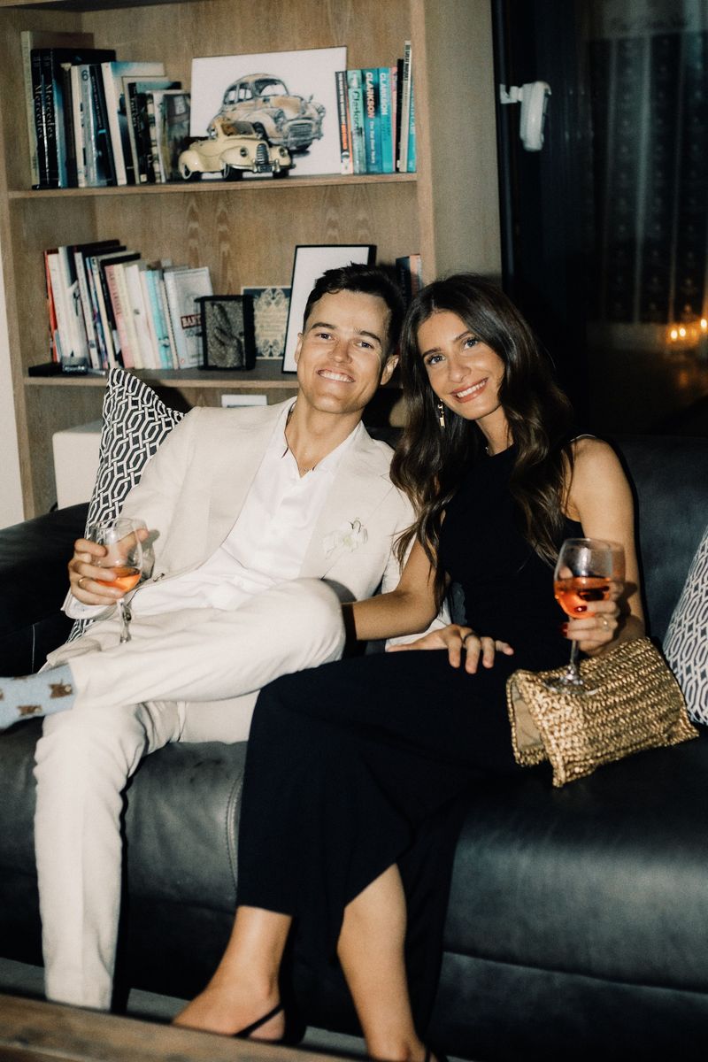 Kyra and Dustin dressed up on a leather couch, drinks in hand