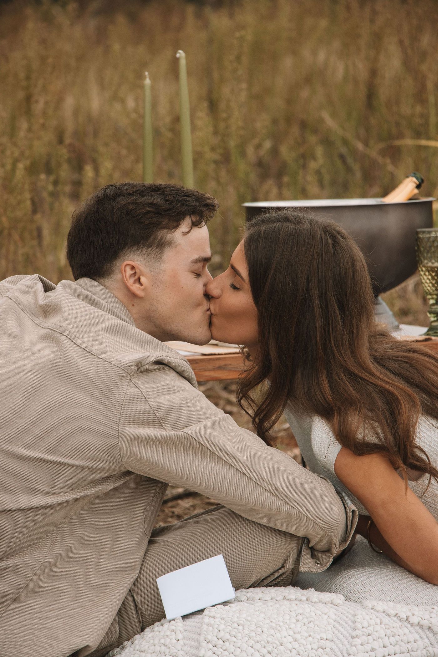 Kyra and Dustin sharing a kiss in a golden grass field